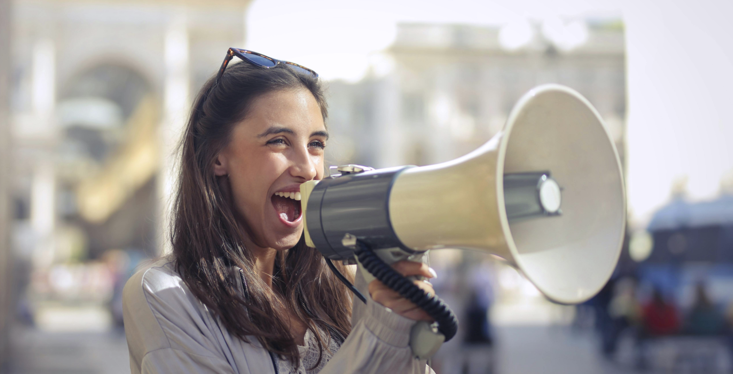 Person yells into a megaphone in front of a city scene