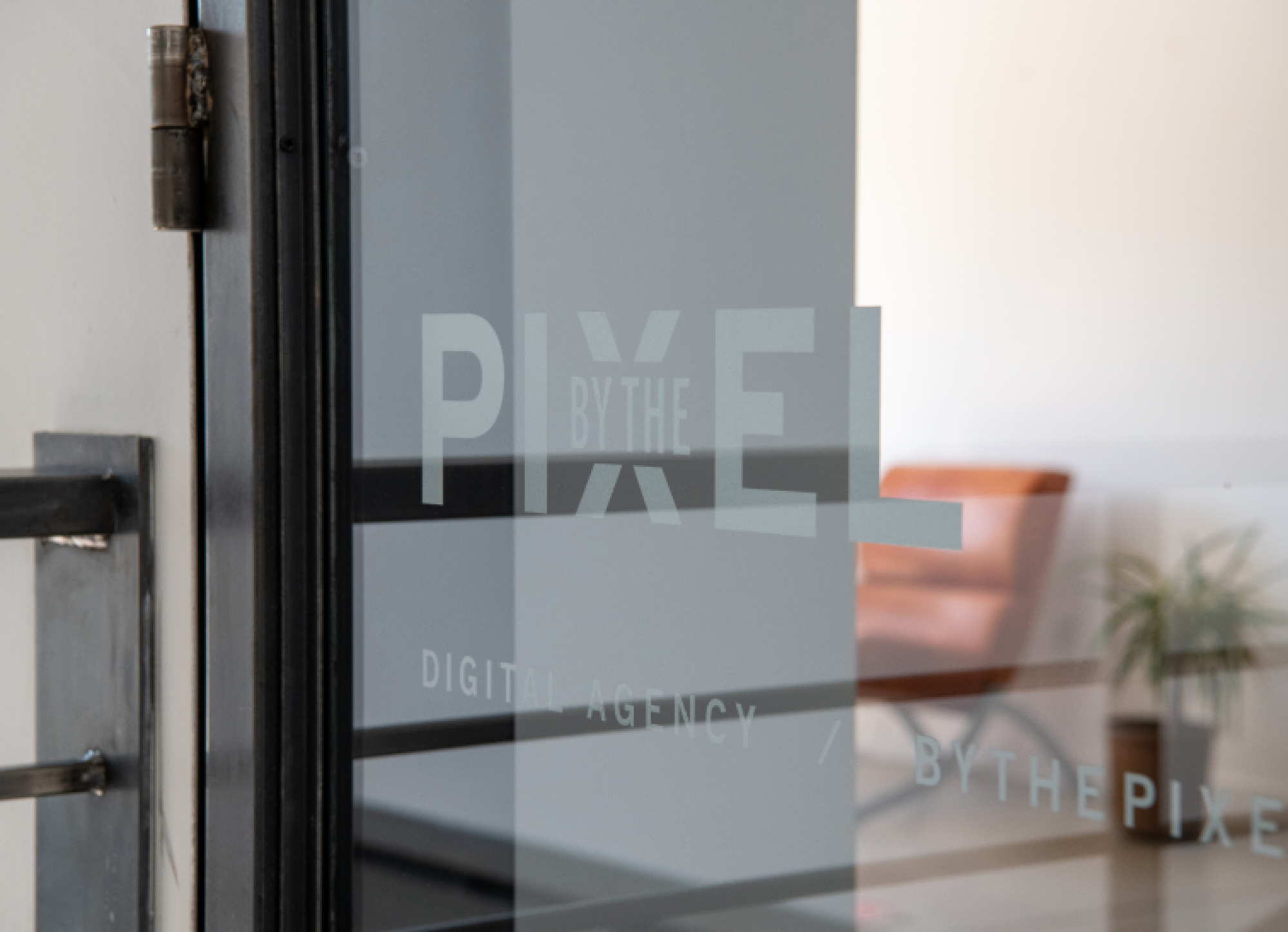 A glass door with the By the Pixel logo